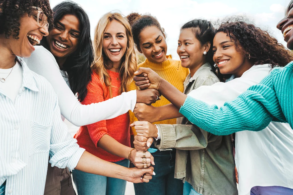 Multicultural group of women stacking hands together